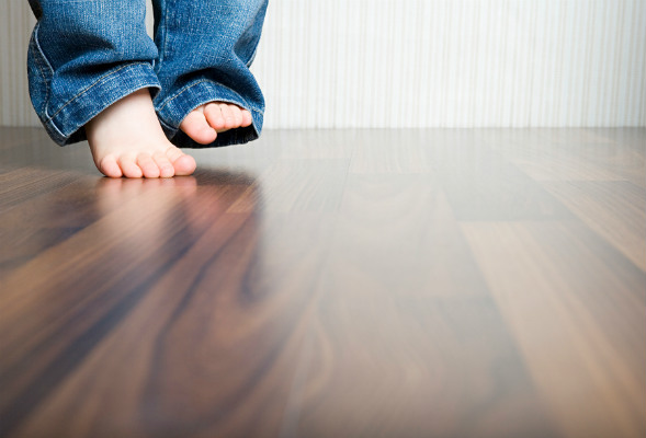 Barneføtter på parkettgulv. Foto.