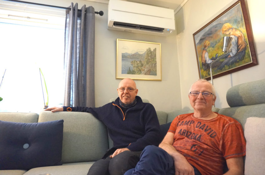 Thorleif og Per-Arne i sofaen med varmepumpen på veggen. Foto.