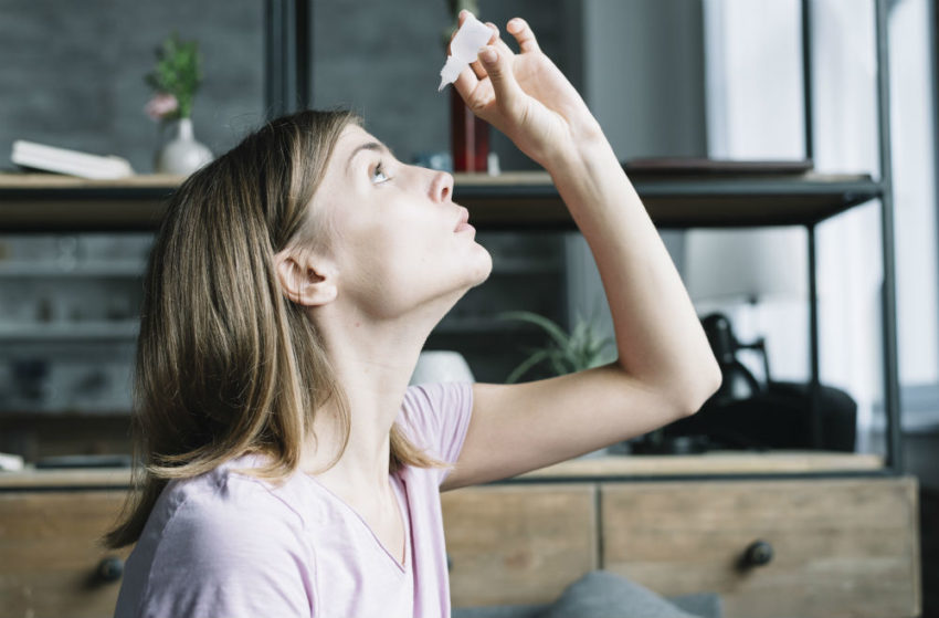 Kvinne drypper øynene sine. Foto.