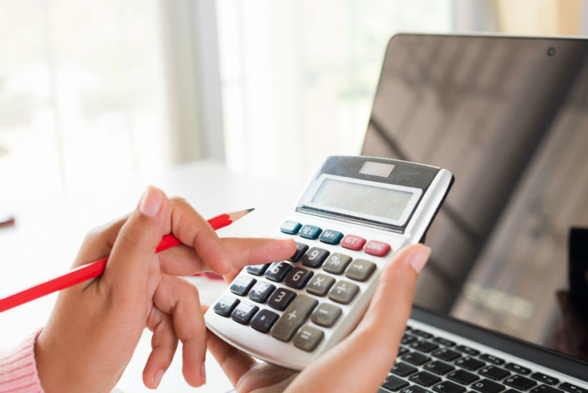 Person taster på kalkulator. Foto.