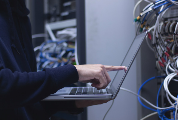 Person med laptop på datarom. Foto.