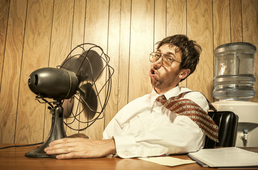 Mann som sitter foran en vifte som blåser kraftig. Foto.