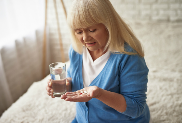 kvinne med medisiner og vannglass. Foto.