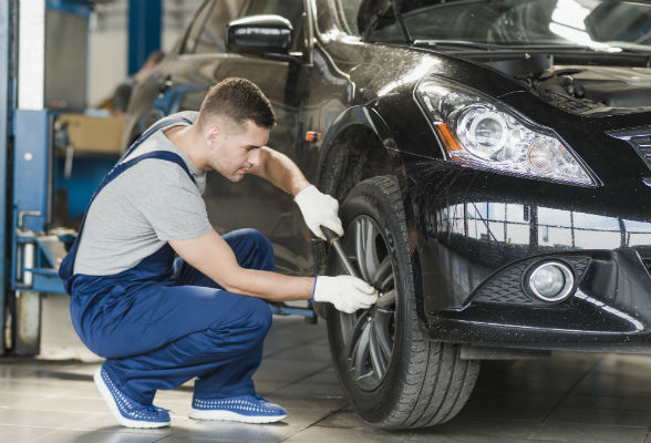 Mann skrur hjul. Foto.