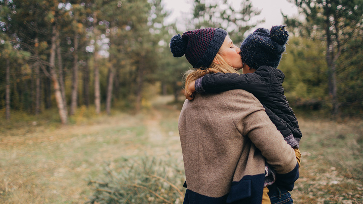 Kvinne med barn på armen ute i naturen. Foto.