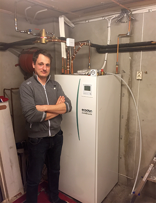 Mann ved siden av Ecodan innedel. Foto.