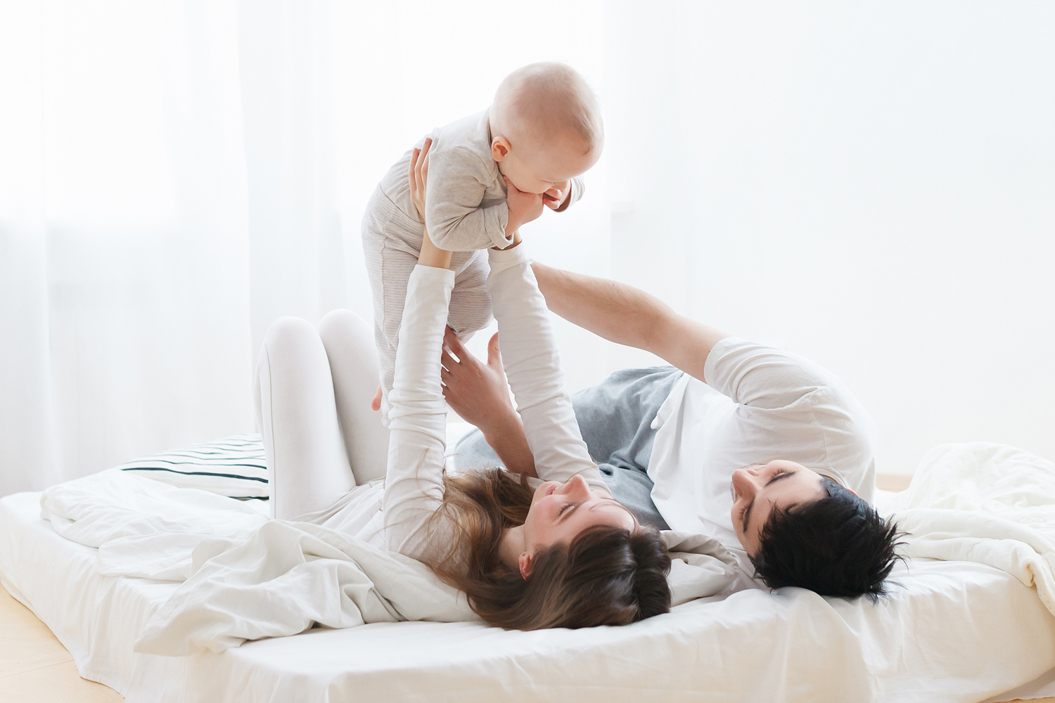 Mor, far og baby på madrass. Foto.