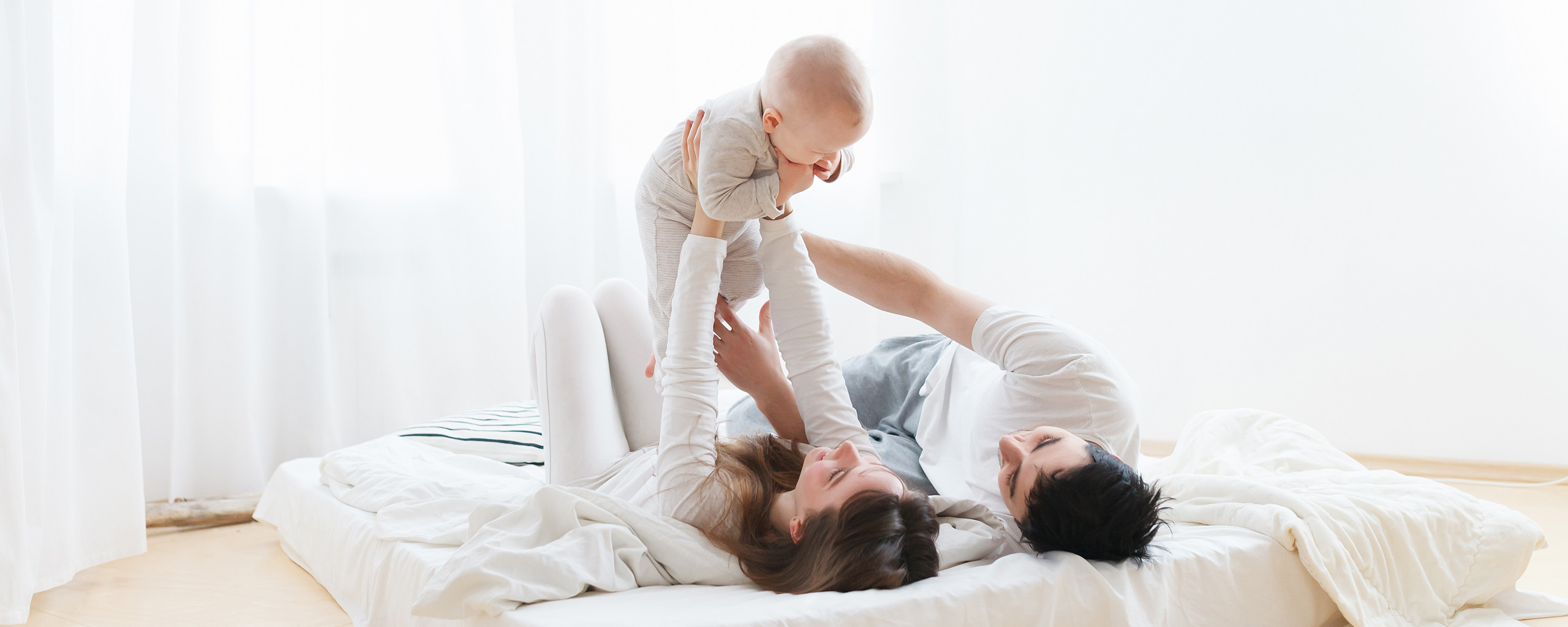 Familie med barn som ligger på madrass . Foto. med en varmepumpe på veggen over dem