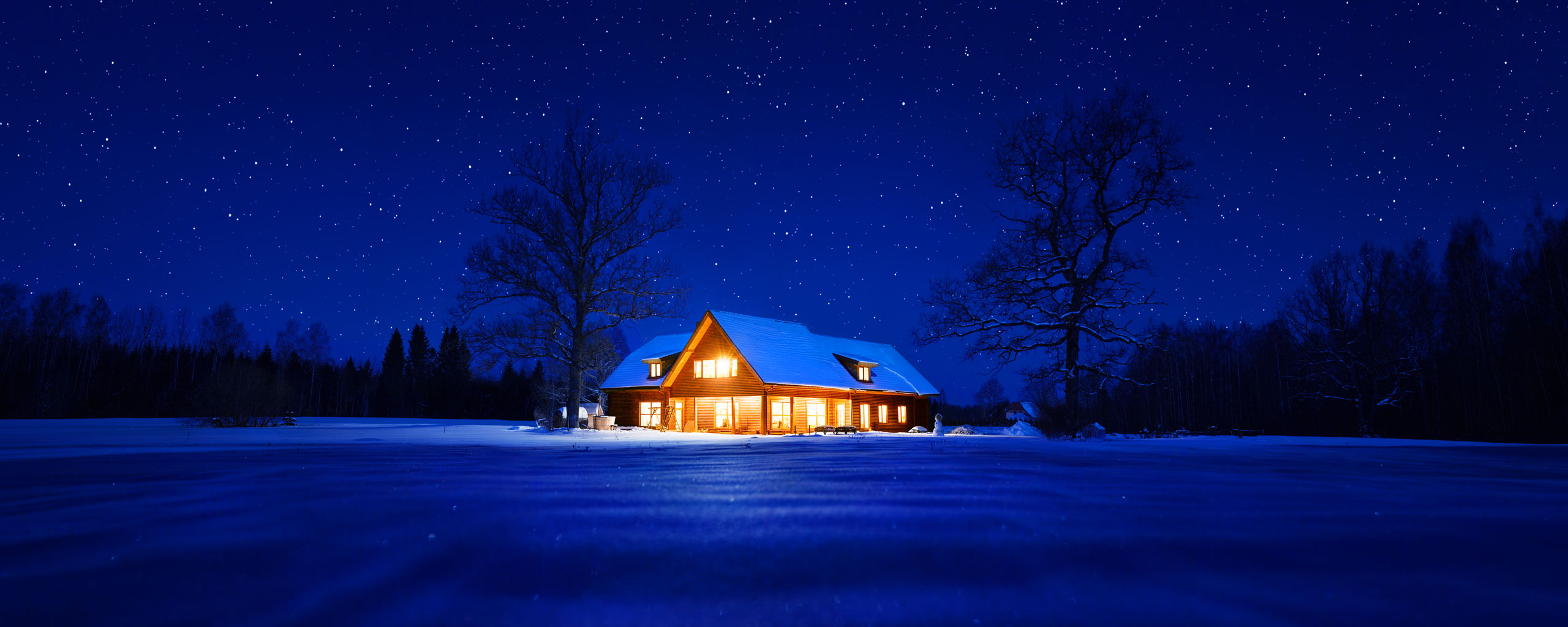 Opplyst hus i mørkt vinterlandskap. Foto.