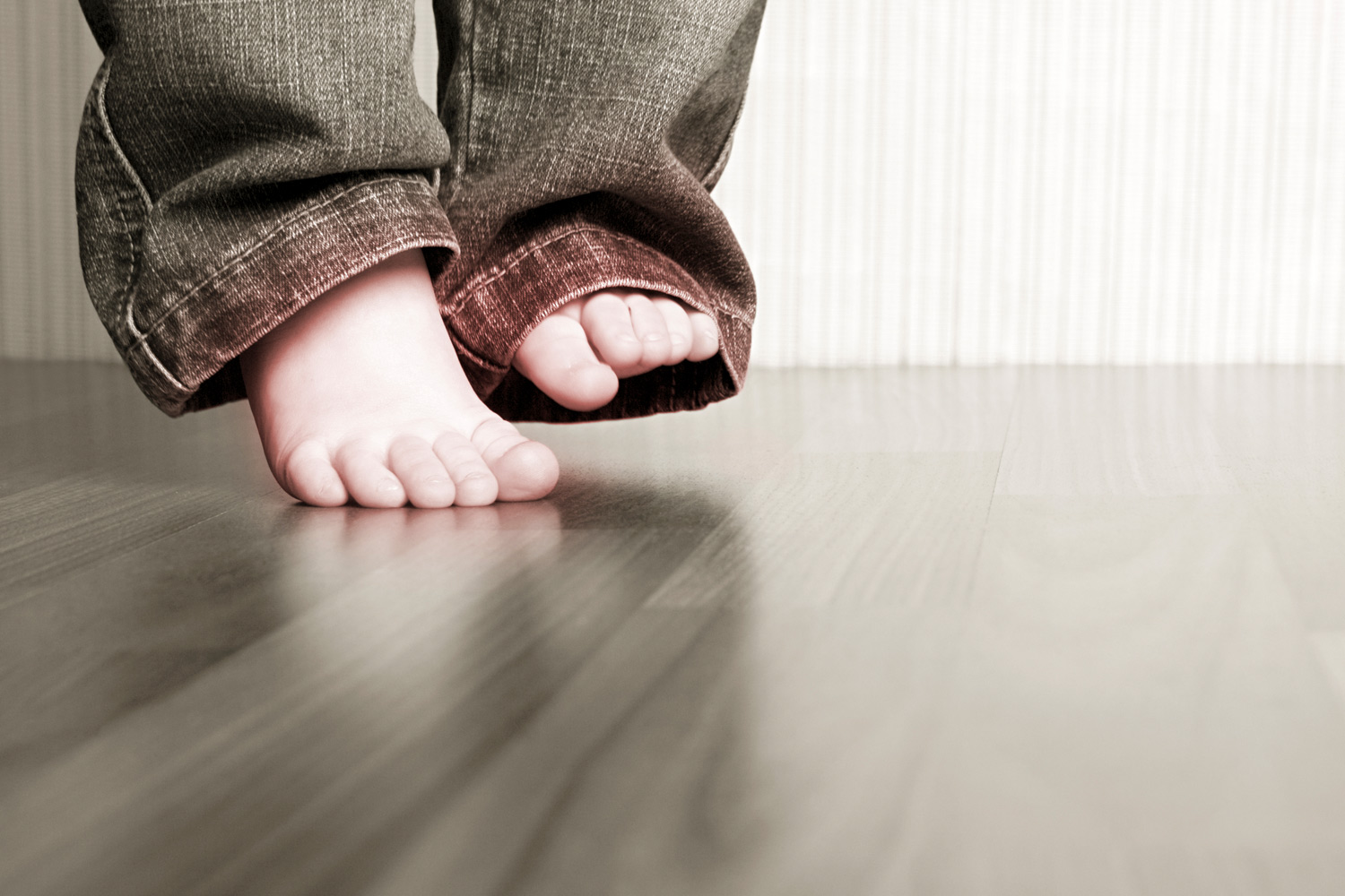 Barneføtter på parkettgulv. Foto.