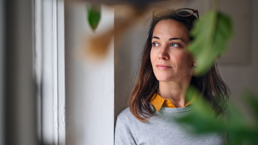 Kvinne som titter ut av vinduet. Foto