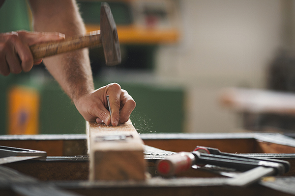 Hender som hamrer spiker. Foto