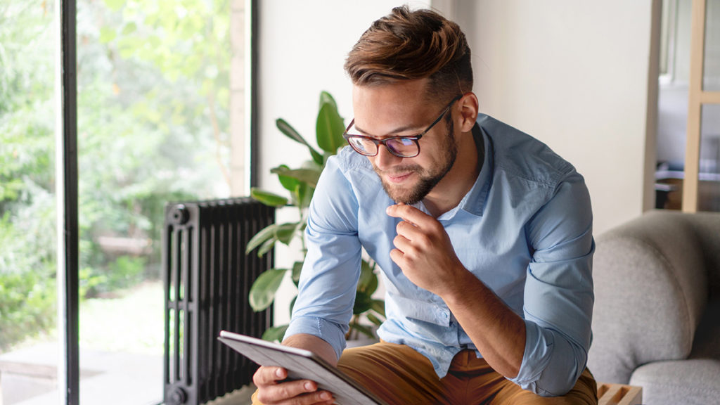 Mann som sitter med nettbrett. Foto.