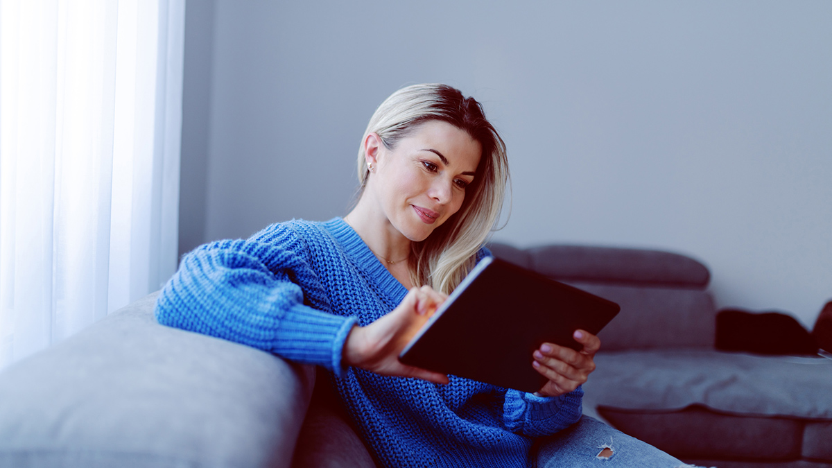 Dame som sitter med nettbrett. Foto.