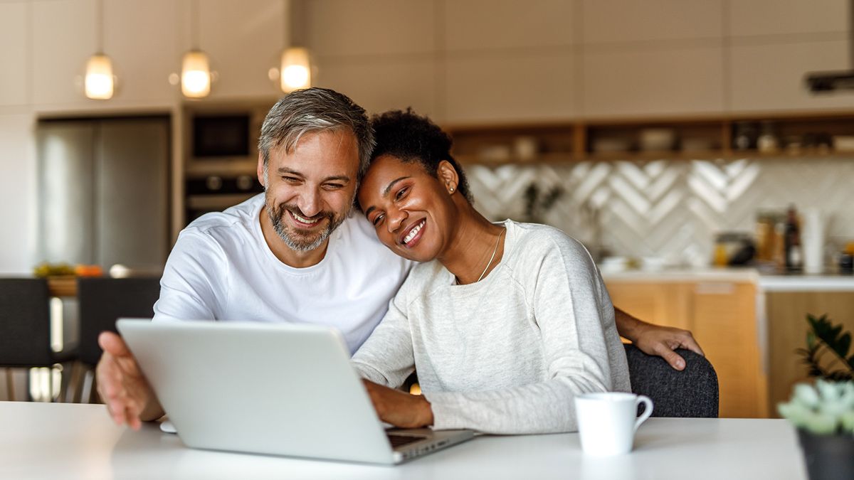 Dame og mann som sitter sammen foran laptop. Foto.