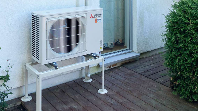 Varmepumpe, utedel, på vegg ute. Foto.